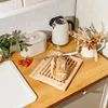 A kitchen counter with a bread cutting board, bread, kettle, and a vase of dried flowers. Produktbild-Vorschau