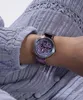 A close-up shot of a woman's wrist wearing a purple Guess watch. Náhled obrázku produktu