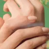 A close-up shot of two hands, with one hand gently touching the other. Náhľad obrázku produktu