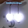 Two heart-shaped LED keychains are illuminated and hanging. Produktbild-Vorschau