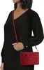A woman wearing a black dress and holding a red handbag. Produktbild-Vorschau