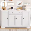 A white sideboard with drawers and doors, decorated with fruit and a coffee maker on top, with marketing overlays. Voir les images du produit