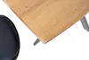 A close-up view of a wooden tabletop with a metal leg and a portion of a black chair. Produktbild-Vorschau