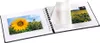 An open spiral-bound photo album with two pages displaying photographs of sunflowers. A protective tissue paper sheet is partially covering the right page. Produktbild-Vorschau