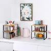 A kitchen counter with two tiered organizers, a kettle, mugs, and decorative items. Produktbild-Vorschau