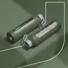 Two olive green glass water bottles with gray lids and white straps are placed on a green surface. Produktbild-Vorschau