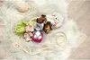 Several small plush toys, including cats and bears, are arranged on a fluffy white rug, with a ball of yarn and a rope nearby. Produktbild-Vorschau
