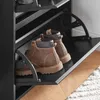 A close-up view of a black shoe cabinet with brown boots stored inside. Produktbild-Vorschau