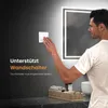A man is interacting with a wall switch next to a backlit mirror in a bathroom. Náhľad obrázku produktu