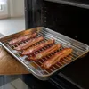 Bacon strips are being cooked on a wire rack inside an oven. Anteprima dell’immagine prodotto