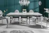 A modern dining room with a white marble-top dining table and chrome legs, surrounded by gray upholstered chairs. Náhled obrázku produktu