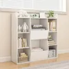A white bookshelf filled with books and decorative items, placed against a window with blinds. Podgląd zdjęcia produktu