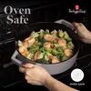 A person is holding a pot of food inside an oven. Anteprima dell’immagine prodotto