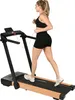 A woman is running on a treadmill with a wood-grain finish. Produktbild-Vorschau