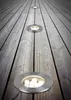 Several round, recessed floor lights are embedded in a weathered wooden deck, receding into the distance. Podgląd zdjęcia produktu