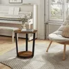 A round side table with two shelves is placed on a rug next to a piano and a chair in a living room. Produktbild-Vorschau