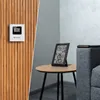 A split image showing a weather station mounted on a wooden wall and another weather station on a small table next to a sofa. Produktbild-Vorschau