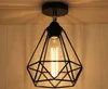 A close-up shot of a black geometric pendant light fixture with an exposed Edison bulb, mounted on a ceiling. Náhľad obrázku produktu