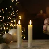 Two LED candles are lit in front of a Christmas tree with lights and ornaments. Produktbild-Vorschau