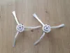 Two white side brushes for a robot vacuum cleaner are laid out on a wooden floor. Náhľad obrázku produktu
