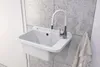 A white sink with a chrome faucet is mounted on a tiled wall. A towel hangs to the right. Anteprima dell’immagine prodotto