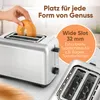 A hand is placing a bagel into a silver toaster. The toaster has extra-wide slots. Produktbild-Vorschau