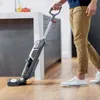 A person is using a vacuum cleaner in a kitchen. Voir les images du produit
