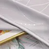 A close-up view of a light gray curtain with a silver geometric pattern and dots, folded over a framed artwork and a magazine. Produktbild-Vorschau