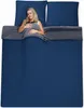 A woman is lying in a bed with dark blue bedding. Produktbild-Vorschau