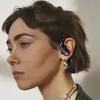 A close-up profile shot of a woman wearing a black wireless earbud with a red accent. Produktbild-Vorschau