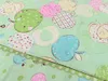 A close-up view of a light green fabric with a repeating pattern of colorful apples. Náhľad obrázku produktu