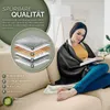 A woman is sitting on a couch, reading a book and wrapped in a heated blanket. Náhľad obrázku produktu