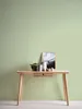 A wooden desk with decorative items against a green wall. Produktbild-Vorschau