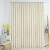 A cream-colored velvet blackout curtain hangs on a curtain rod, with a small chair and a vase of yellow flowers to the left, and a coat rack with a bag and scarf to the right. Náhled obrázku produktu