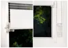 A collage showing two close-up views of a white roller blind with a red stripe, installed on a window with a view of green trees outside. Produktbild-Vorschau