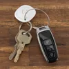 A set of car keys and a Bluetooth tracker are placed on a wooden surface. Anteprima dell’immagine prodotto