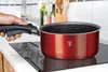 A hand is holding the handle of a red pot on an induction stovetop. Podgląd zdjęcia produktu