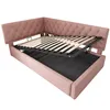 A pink upholstered corner bed frame with the mattress support system lifted to reveal storage space underneath. Produktbild-Vorschau