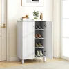 A white shoe cabinet with its doors open, displaying shoes on shelves, placed in a hallway next to a door. Produktbild-Vorschau