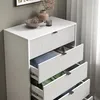 A white dresser with fluted drawer fronts, some drawers are open showing folded clothes inside. The top of the dresser has decorative items. Podgląd zdjęcia produktu