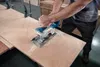 A person is using a cordless circular saw to cut a piece of wood. Produktbild-Vorschau