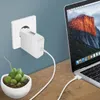 A white MacBook Air charger is plugged into a wall socket and connected to a MacBook Air laptop, with a small potted plant in the foreground. Produktbild-Vorschau