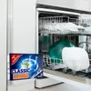 A box of dishwasher tabs is placed in front of an open dishwasher filled with dishes. Produktbild-Vorschau