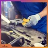 A mechanic in a blue uniform and white gloves is holding a pair of pliers over a car engine. Produktbild-Vorschau
