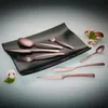 A set of bronze-colored cutlery is arranged on a black plate, with mushrooms and parsley as decoration. Produktbild-Vorschau