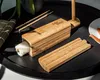A bamboo sushi-making kit is shown on a black tray, with chopsticks and a partially made sushi roll. Náhľad obrázku produktu