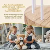 Two young girls are playing with a teddy bear in a room with shelves filled with stuffed animals. Produktbild-Vorschau