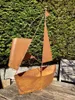 A rusty metal sailboat sculpture is placed on a wooden table in a garden setting, with a green hedge in the background. Produktbild-Vorschau
