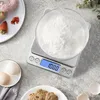 A digital scale with flour in a clear bowl, next to eggs and cookies. Produktbild-Vorschau