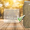 A bag of birdseed is shown next to a transparent overlay listing the ingredients, with a wooden table and a blurred background of trees. Produktbild-Vorschau